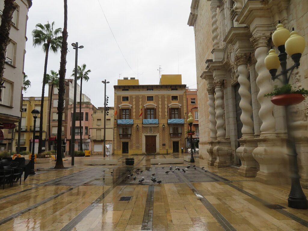 San Bartolomé Square in Benicarló with the town hall facade, palm trees and wet paving after rain
