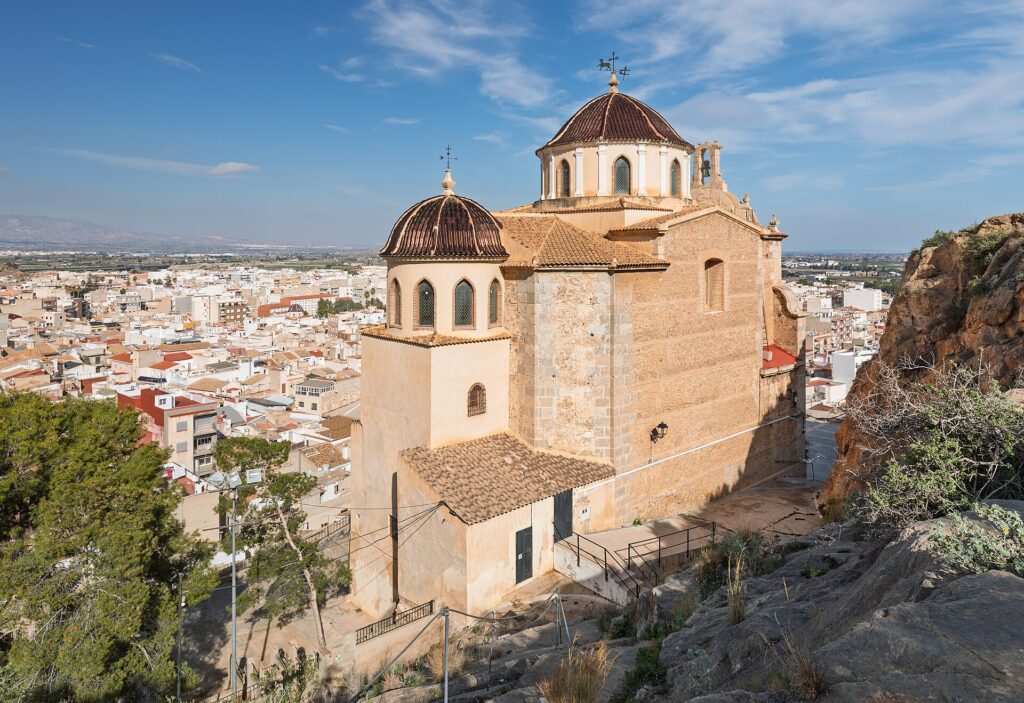 Sanctuary of Saint Roch on a rocky outcrop above the white houses of Callosa de Segura under a blue sky