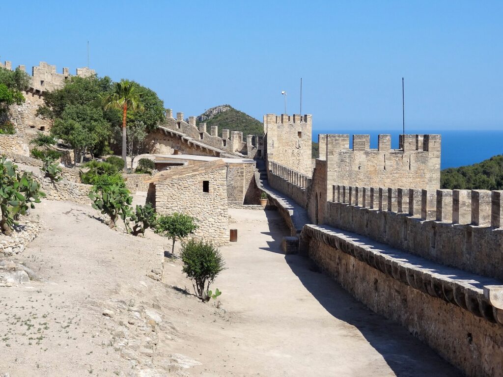 Crenellated walls and towers of Capdepera Castle on Mallorca with the sea behind
