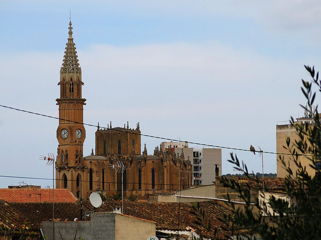 Bell tower and Gothic church of Nostra Senyora dels Dolors rising above the rooftops of Manacor, Mallorca
