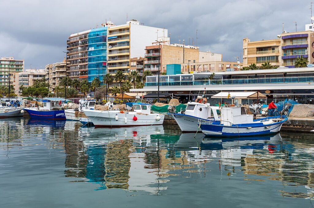 Fishing boats and yachts reflected in the calm water of Santa Pola harbour