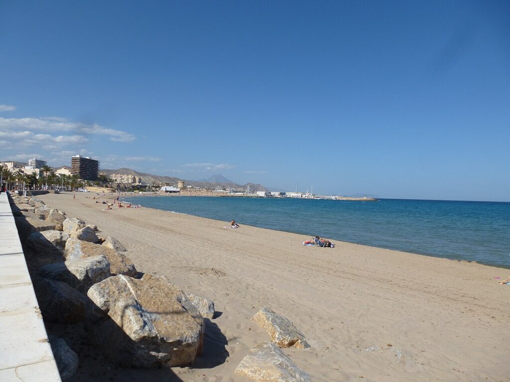 The sandy beach and stone breakwater of El Campello beside a calm blue sea
