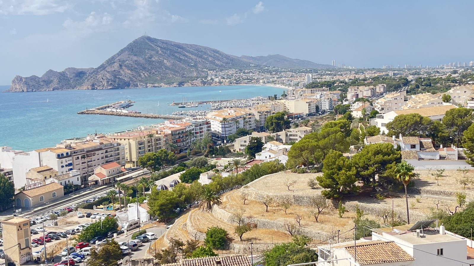 The bay of Altea seen from the old town: the marina and breakwater, the town along the shore, the Serra Gelada headland closing the bay and Benidorm's towers on the far horizon