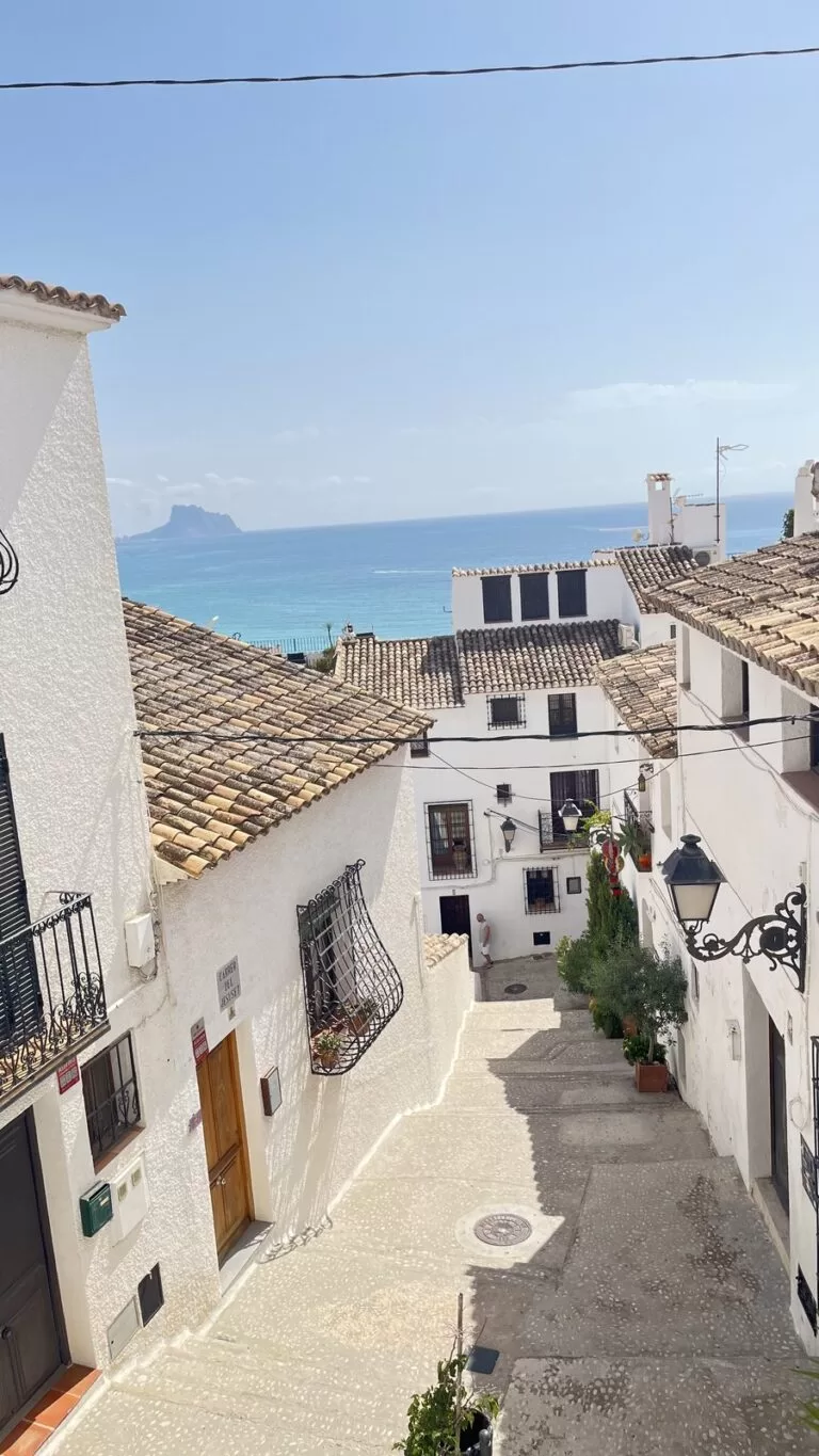 Carrer del Jesuset in Altea old town, white houses and tiled roofs, with the Peñón de Ifach on the horizon