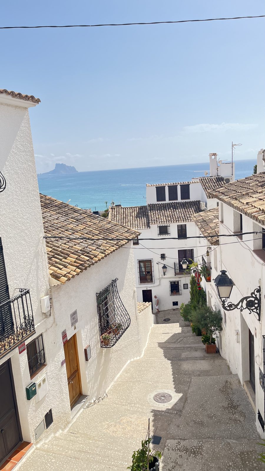 Carrer del Jesuset in Altea old town, white houses and tiled roofs, with the Peñón de Ifach on the horizon