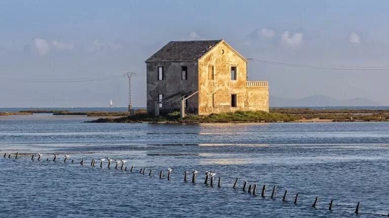 An old stone fishing house standing in the shallow Mar Menor among fish traps