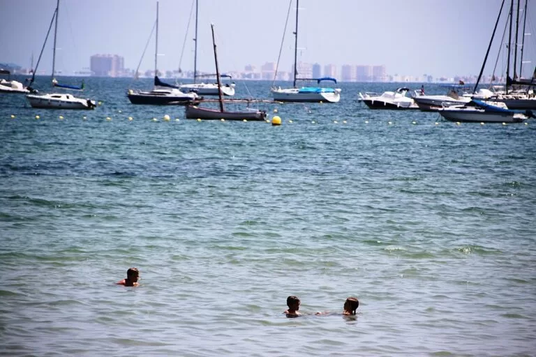 Sailing boats at anchor and swimmers in the calm Mar Menor at Los Alcázares