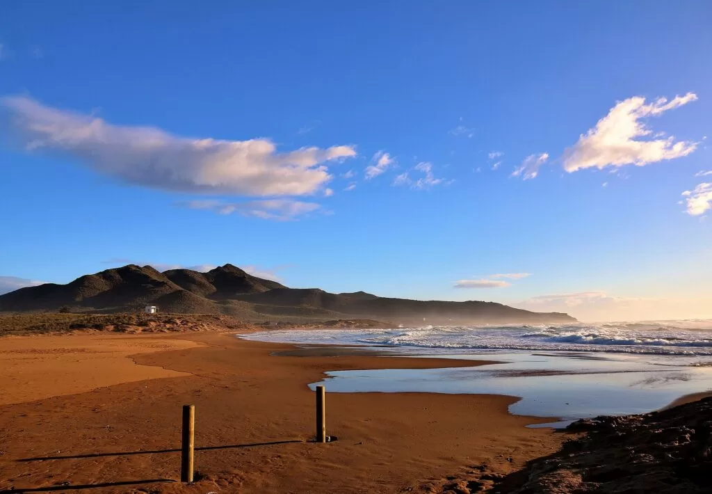 Red sand and a calm bay at Playa de Calblanque under an evening sky
