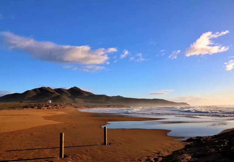 Red sand and a calm bay at Playa de Calblanque under an evening sky