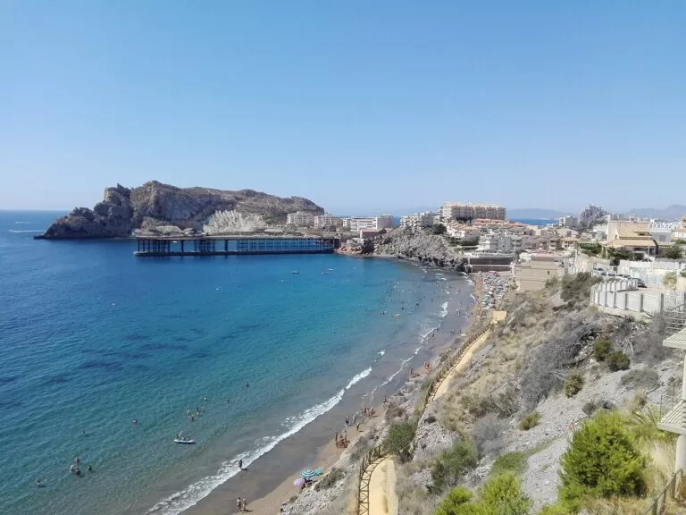 The blue bay of El Hornillo in Águilas with the old loading pier and the island beyond