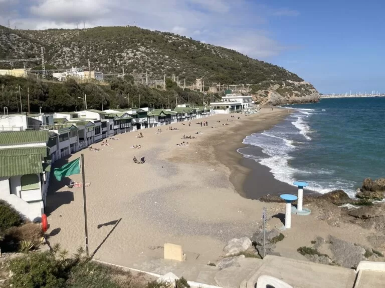 The small beach of Garraf below green coastal hills