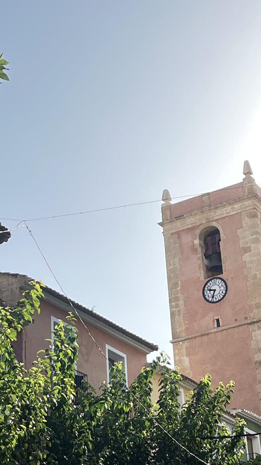 Bell tower and clock face of the fortress church of the Asunción rising above the old town of Villajoyosa