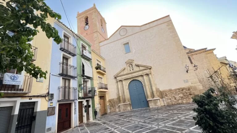 The fortress church of Nuestra Señora de la Asunción in Villajoyosa, with its Baroque portal and coloured houses on the Plaça de l'Església