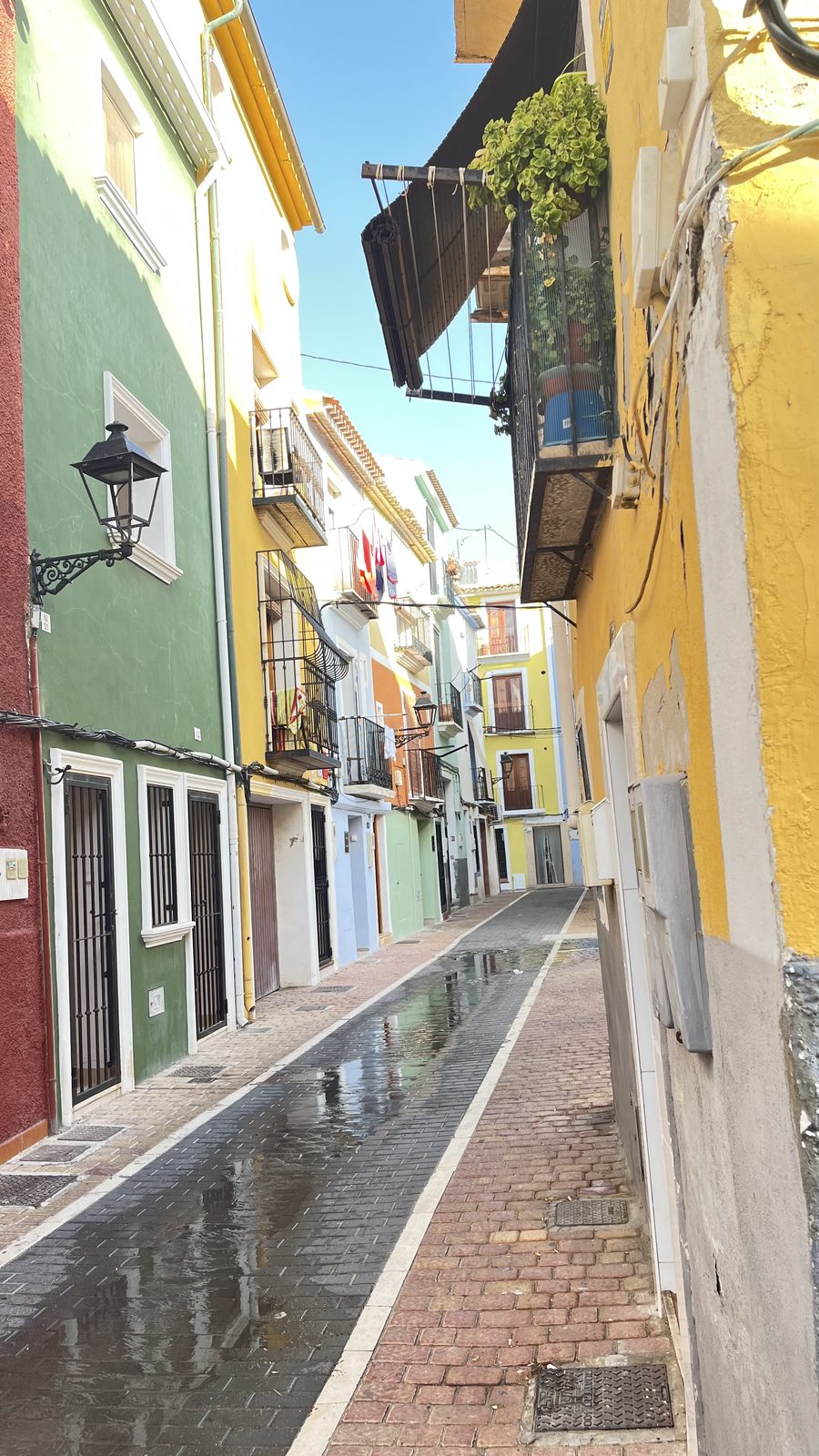Green and yellow painted houses along a narrow paved street in the old town of Villajoyosa